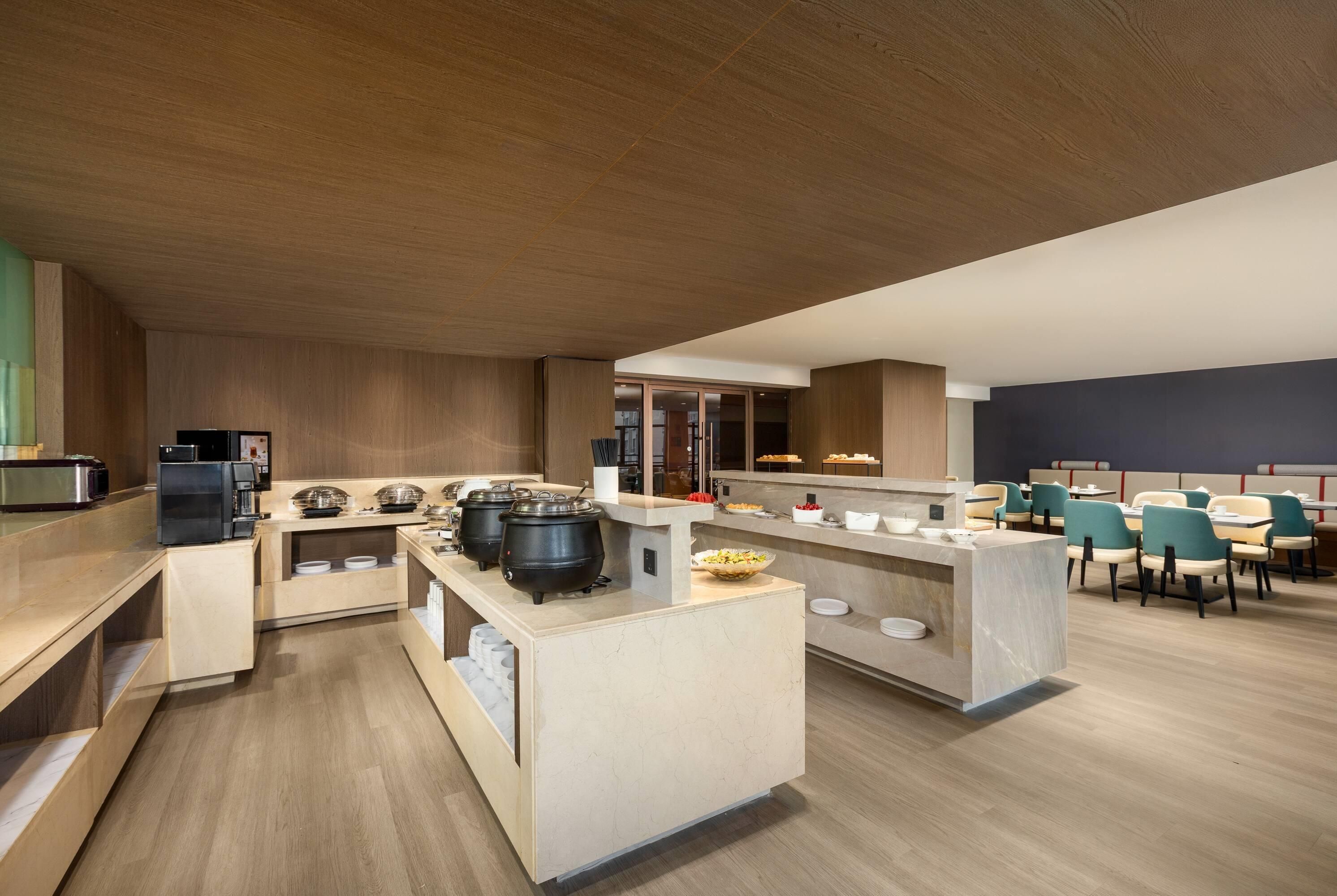 A modern cafe with a central counter, seating area, and kitchen appliances.
