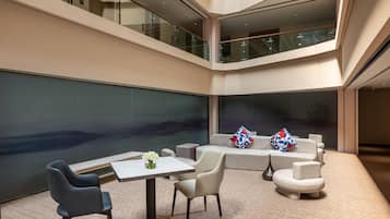 A spacious, multi-level atrium with a seating area featuring a sofa and chairs, a small table, and decorative pillows.