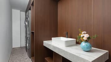 A modern bathroom with a marble countertop, a white sink, and a vase with flowers.