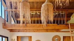 A rustic interior with a wooden dining table, woven chairs, a sofa with cushions, and a ceiling with hanging light fixtures. - Lodge des Baronnies - Les Cabanes de Provence (Plaisians)