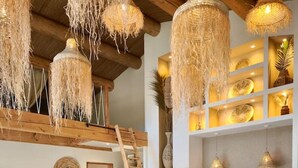 A modern interior with a wooden dining table, wicker chairs, and a ladder leading to a loft area. - Lodge des Baronnies - Les Cabanes de Provence (Plaisians)