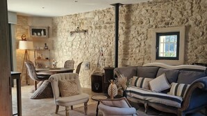 A living room with stone walls, a fireplace, a sofa, armchairs, and a coffee table.