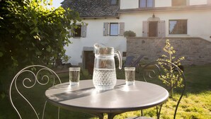 Une terrasse avec une table, deux chaises, une carafe et deux verres.