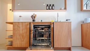 Cozinha com lava-louças embutida, armários de madeira e bancada com utensílios de cozinha.
