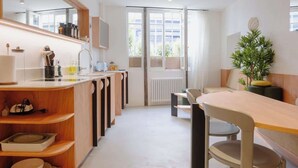 Uma cozinha moderna com uma ilha central, um espaço de refeições com mesa e cadeiras, e uma janela grande que oferece luz natural.