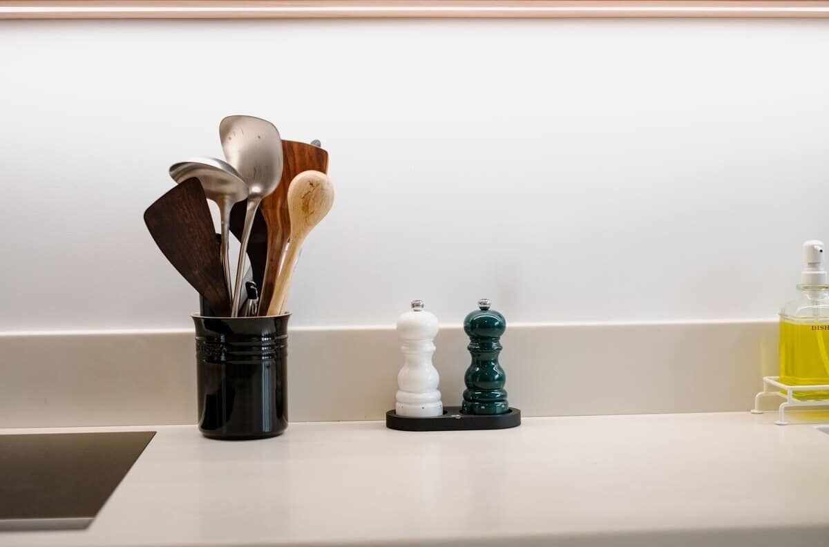 A kitchen counter with utensils, salt and pepper shakers, and a bottle of dish soap.