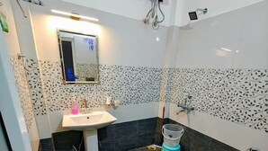 Un baño con lavamanos blanco, un espejo, inodoro y zona de ducha.
