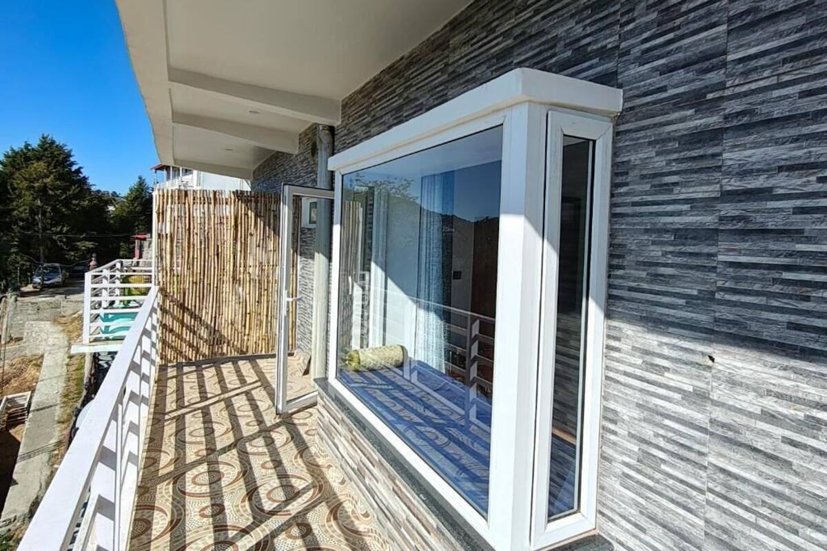 Un bâtiment moderne doté d’une grande baie vitrée, d’un balcon au revêtement de sol à motifs et d’un mur en pierre.