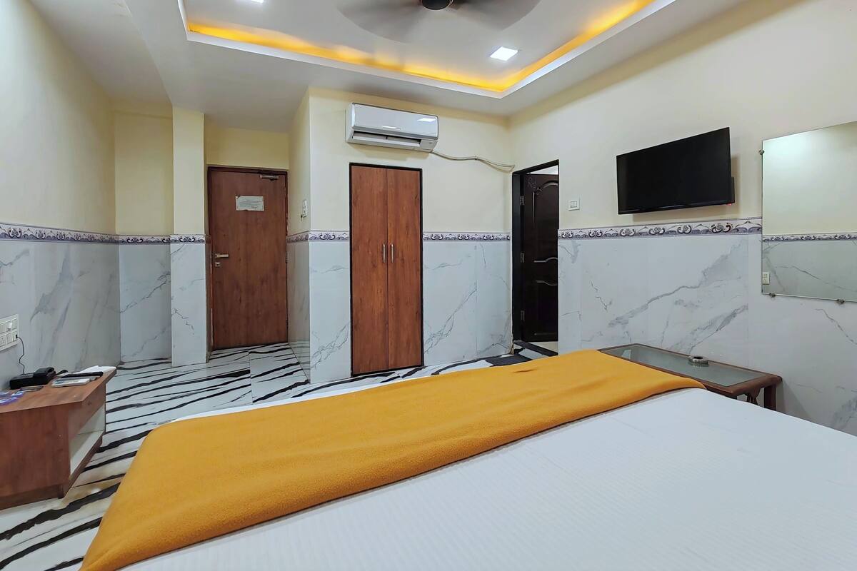 Une chambre d’hôtel équipée d’un lit, d’un bureau, d’un climatiseur, d’un ventilateur de plafond et d’une télévision.