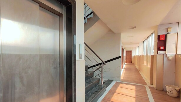A modern hotel corridor with a wooden floor, a staircase, and a door.