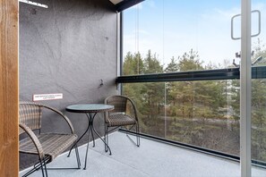 A balcony with wicker chairs, a small round table, and a sign in a foreign language. - Arctic Railway Studio by Lapland Host (Rovaniemi)