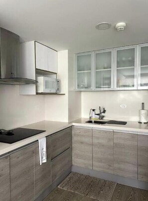 Eine moderne Küche mit Holzausstattung, integriertem Mikrowellenherd und einer Spüle aus Edelstahl.