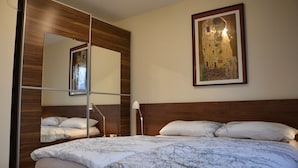 Una habitación de hotel con una cama grande, cabecera de madera, un espejo y un cuadro en la pared.