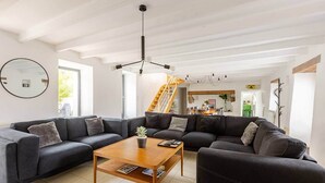 Een moderne woonkamer met een hoekbank, een salontafel en een trap die leidt naar een eethoek.