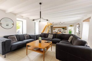 Ein modernes Wohnzimmer mit Ecksofa, Couchtisch und einer Treppe, die in einen Essbereich führt.