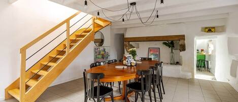 Ein Essbereich mit einer Holztreppe, einem Chandelier und Blick in einen anderen Raum.