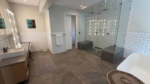 A modern bathroom with a glass-enclosed shower, a large mirror, and a white bathtub. - Room-tuna Room - Staynest Guesthouse (Ballito)