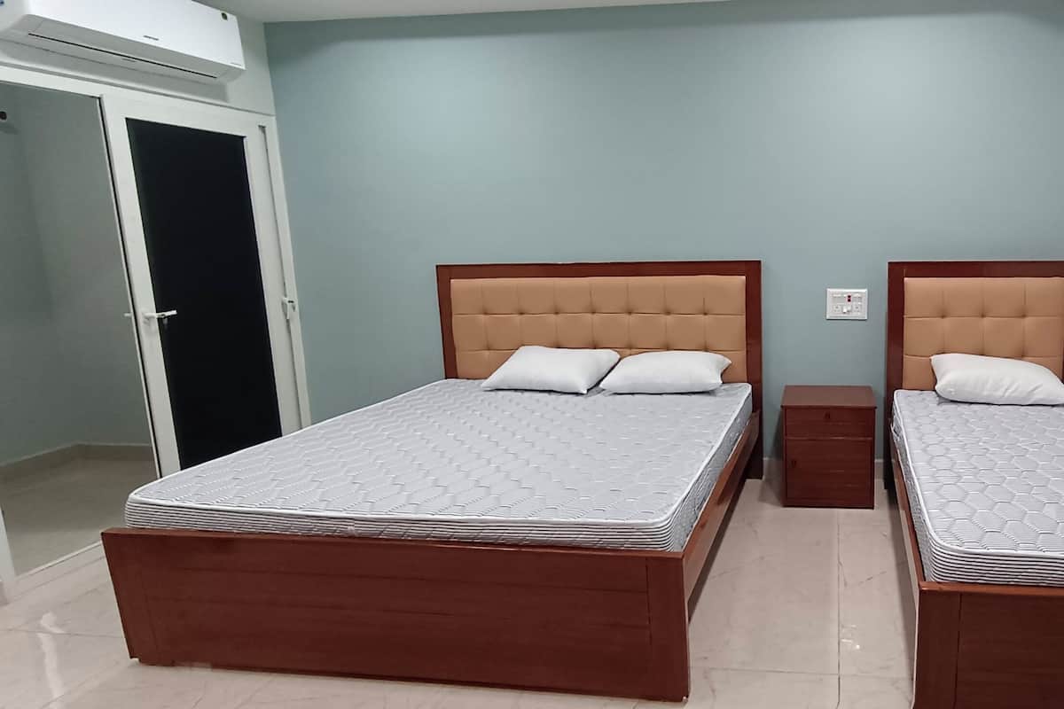 A room with two beds, a small wooden nightstand, and a door.
