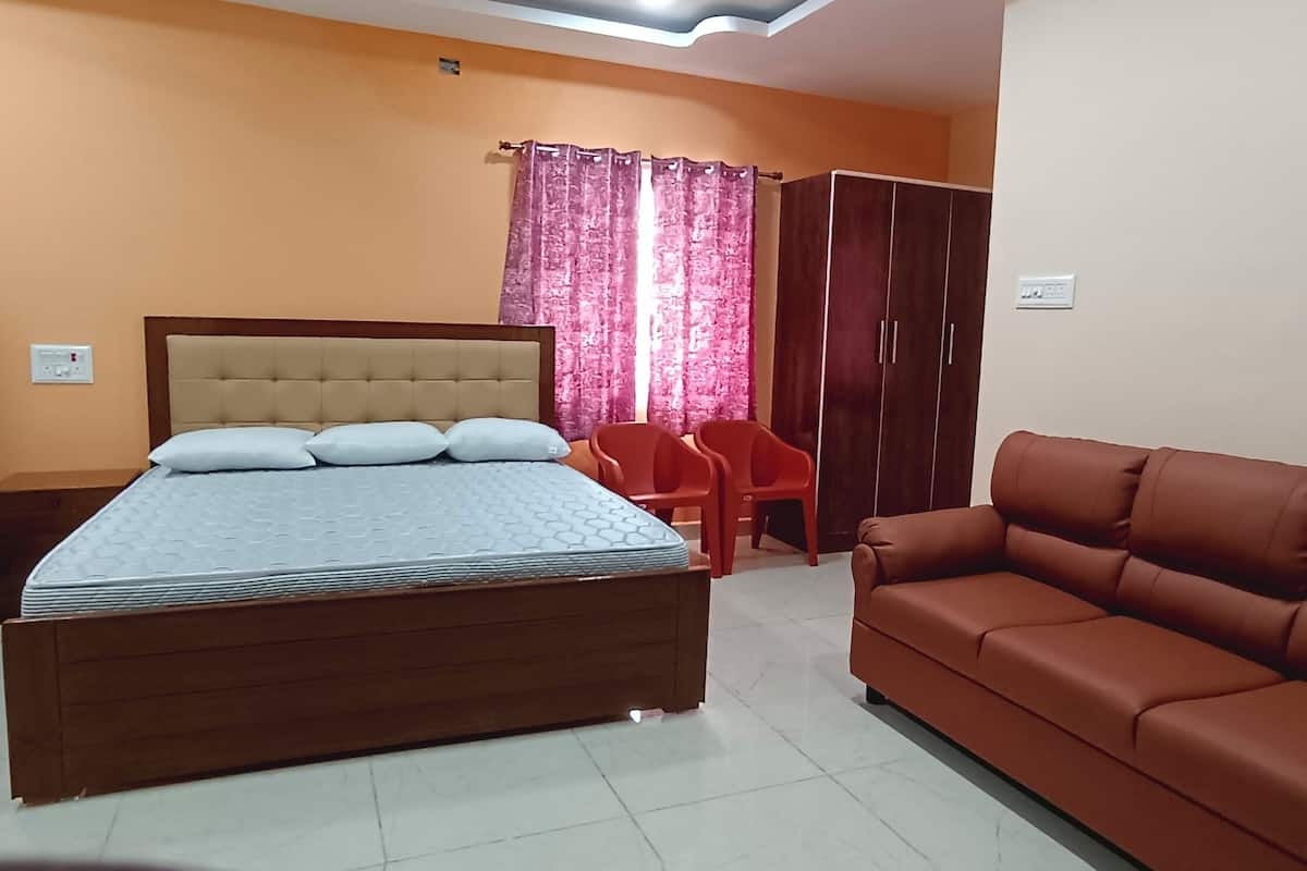 A room with two beds, a sofa, a wardrobe, and a curtain.