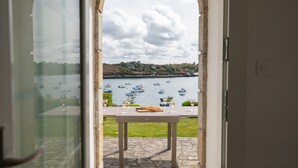 Vista attraverso un arco su un tavolo con bicchieri e una baguette, con vista su un'acqua dove si vedono barche.