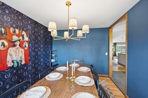 A dining area with a blue wall, a chandelier, and a large painting.