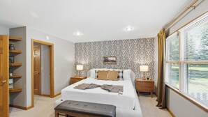 A bedroom with a bed, bedside tables, a bench, a wardrobe, and a window with blinds. - Loveland Luxury Getaway | Pool | Golf Course (Loveland)