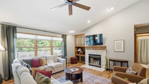 A living room with a sofa set, a coffee table, a fireplace, a television, and a ceiling fan. - Loveland Luxury Getaway | Pool | Golf Course (Loveland)