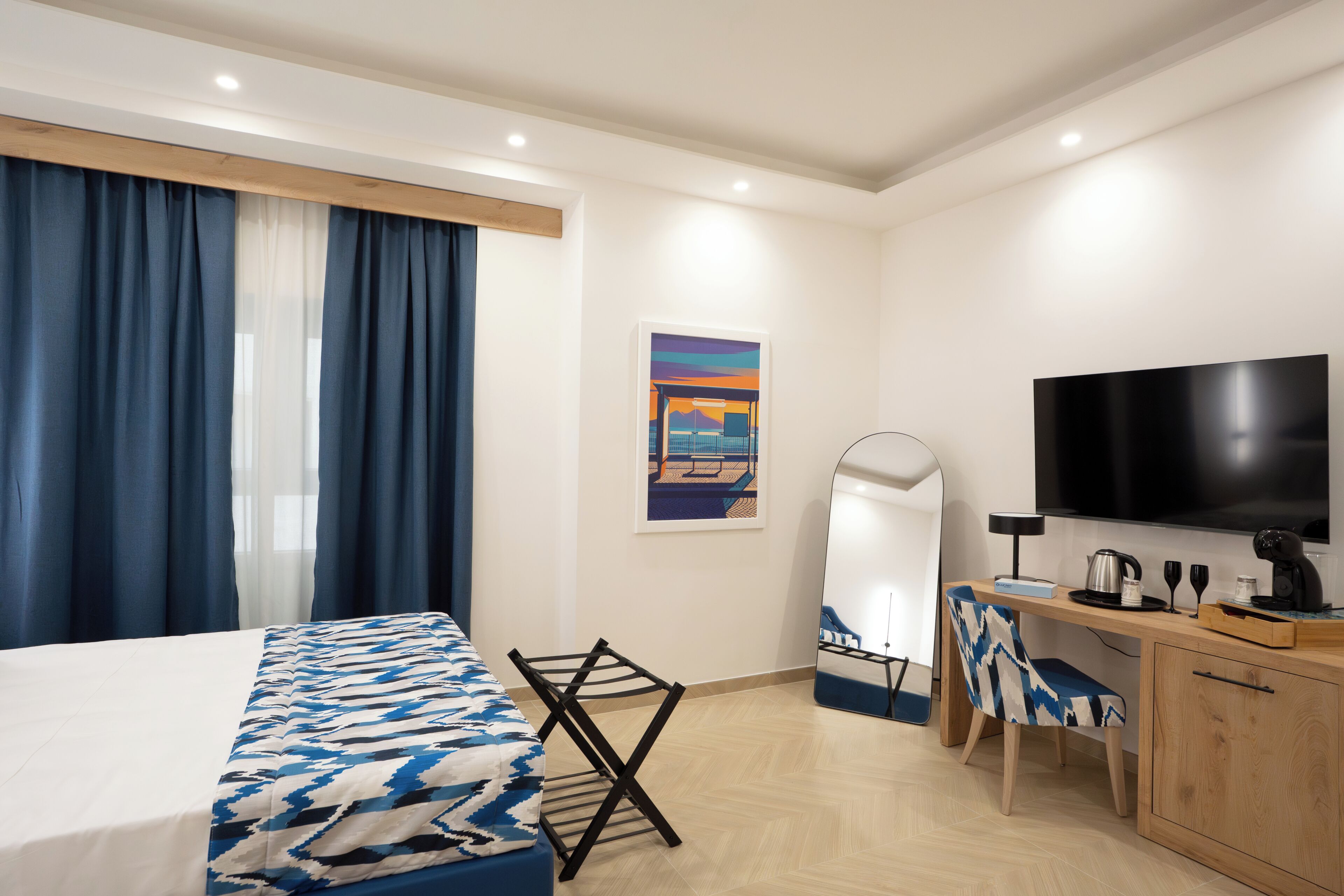 Habitació d'hotel amb un llit, escriptori, cadira, televisió i un quadre a la paret.