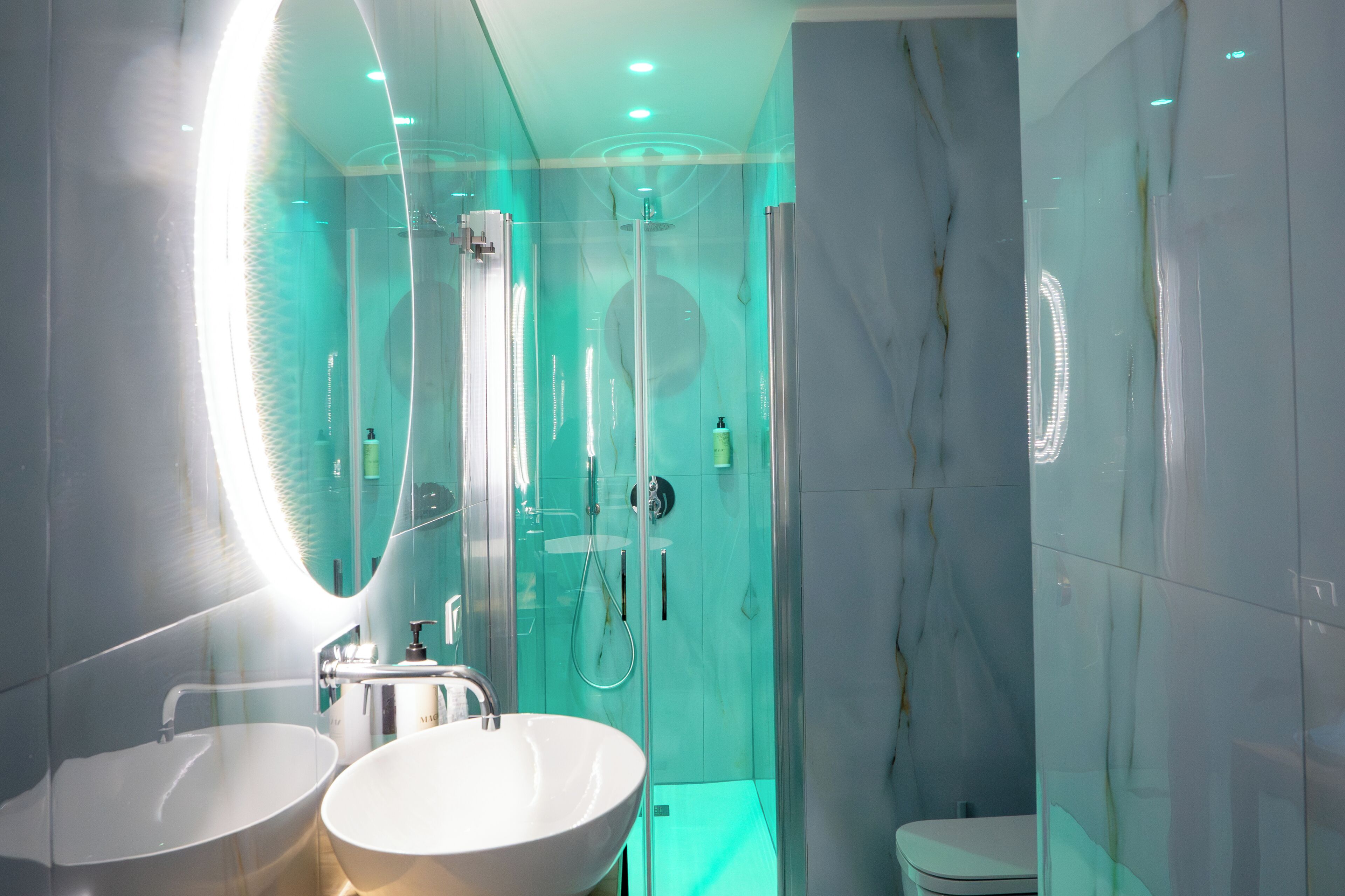 A modern bathroom with two sinks, a toilet, and a glass-enclosed shower.