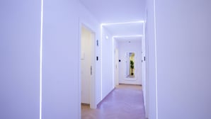 A modern hallway with white walls, wooden flooring, and recessed lighting. - Cervantes LR Collection (Naples)
