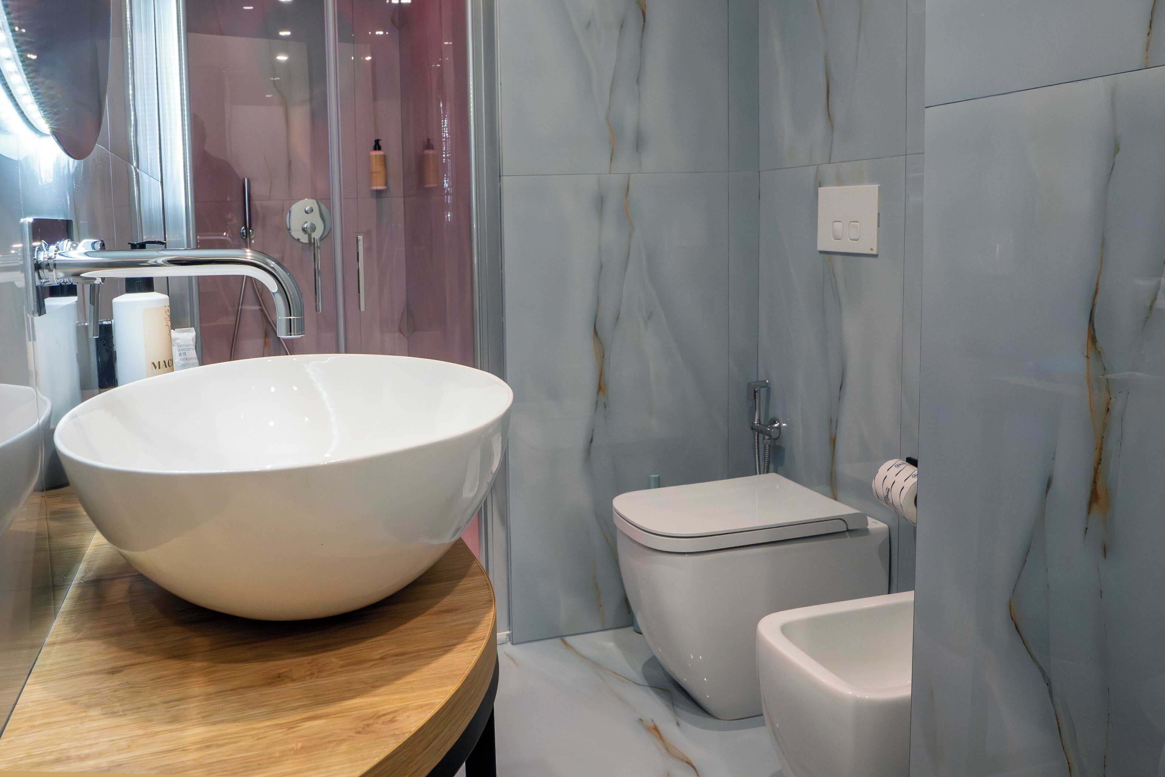 Une salle de bain moderne avec un grand lavabo sur pied blanc, des toilettes et un espace douche.