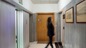 A corridor with a wooden door, a framed picture on the wall, and a doormat with text. - Cervantes LR Collection (Naples)
