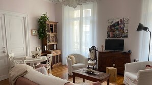 Olohuone, jossa on sohva, nojatuoleja, sohvapöytä, televisio ja kirjahylly.