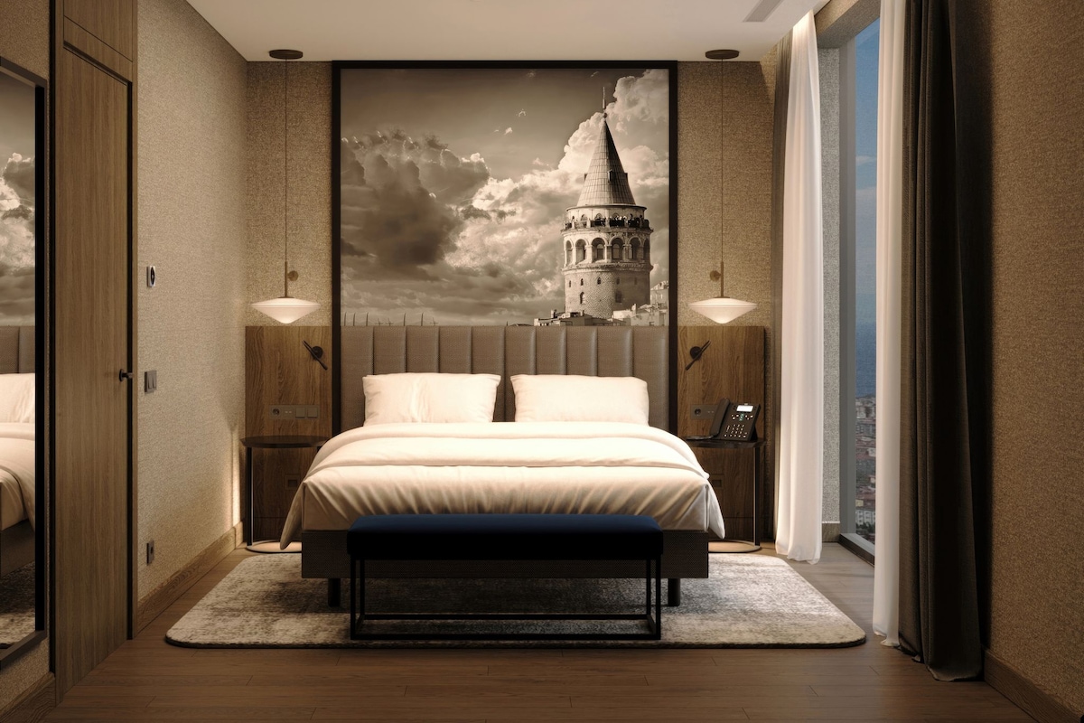 Habitación de hotel moderna con una cama grande, un mural de paisaje urbano en la pared y vistas de la ciudad a través de la ventana.