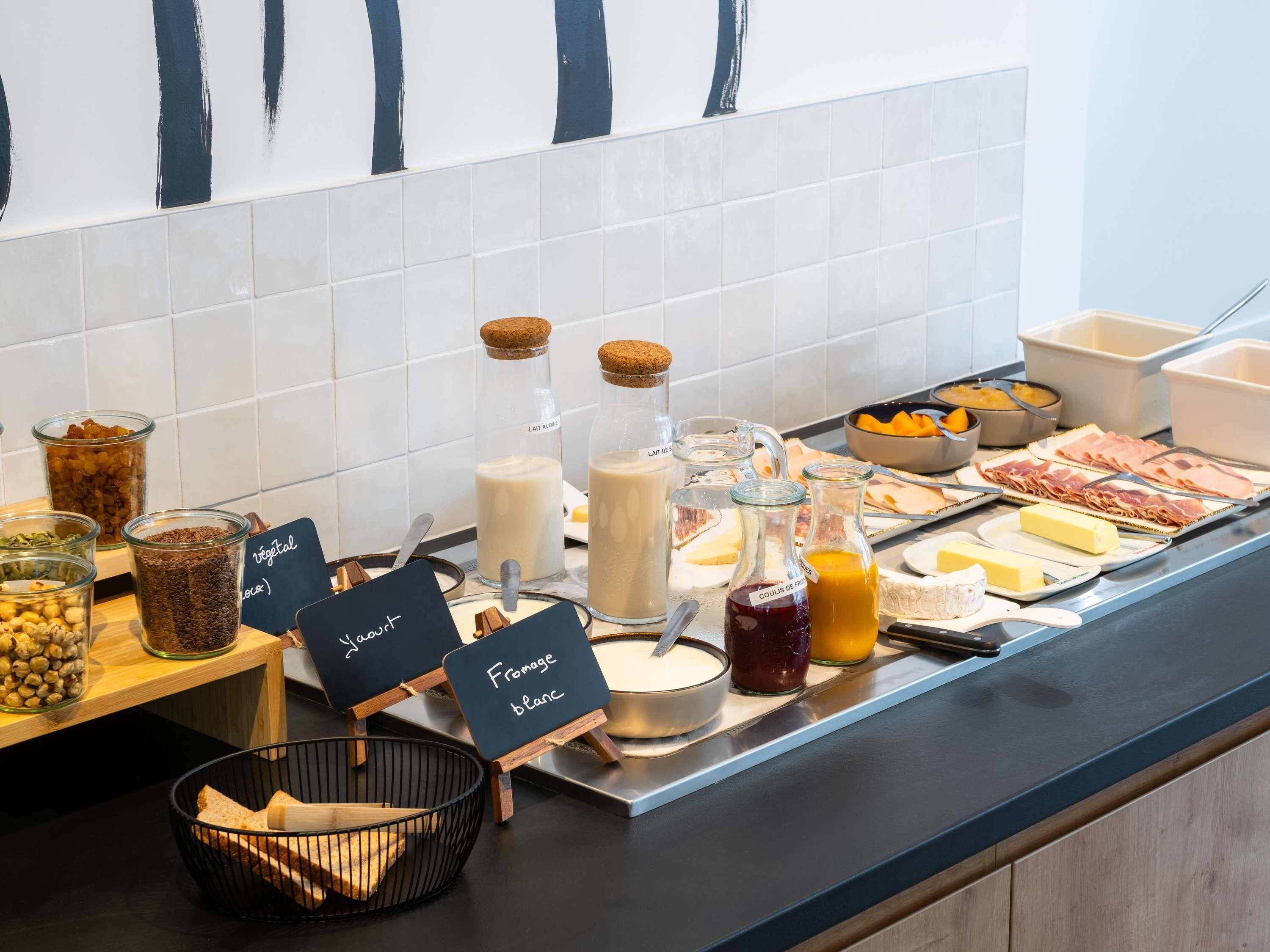A buffet with various food items and condiments, including cheese, meats, and beverages.