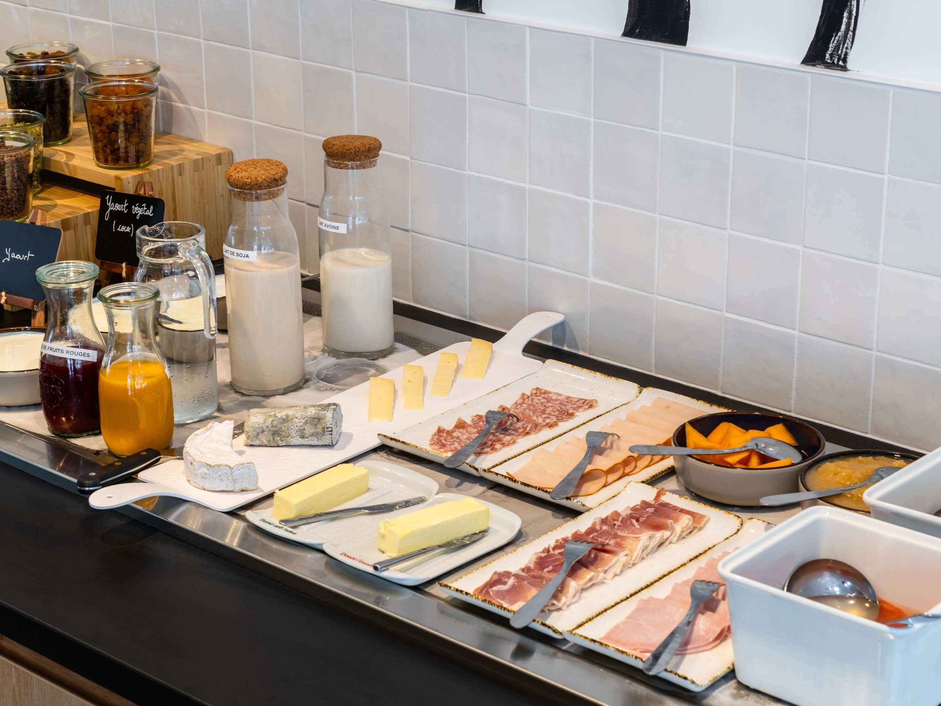 A buffet with various food items including cheese, meats, and condiments.