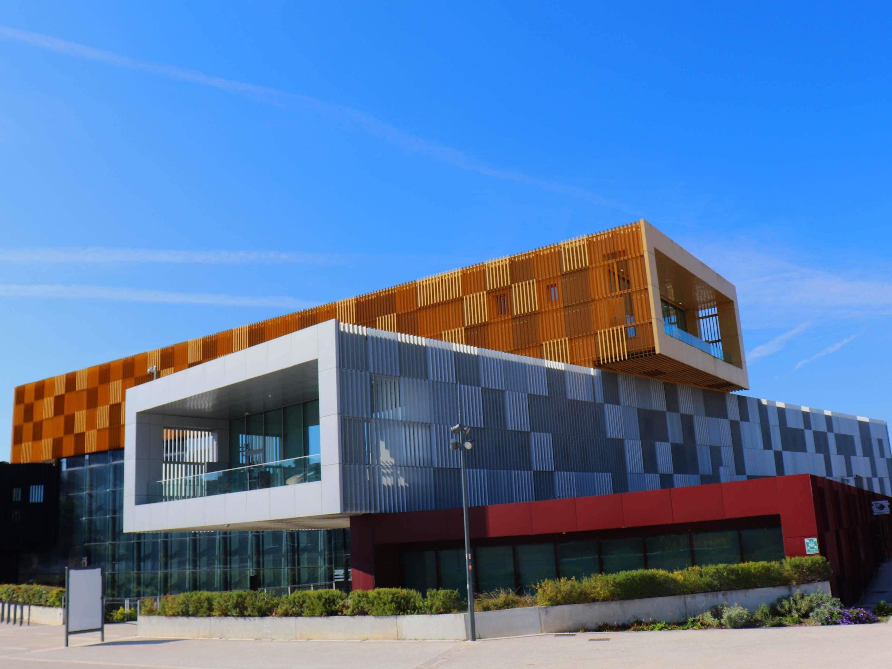 A modern building with a mix of glass and wooden facades, large windows, and a flat roof.