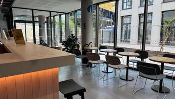 Um café moderno com balcão, área de estar e grandes janelas.