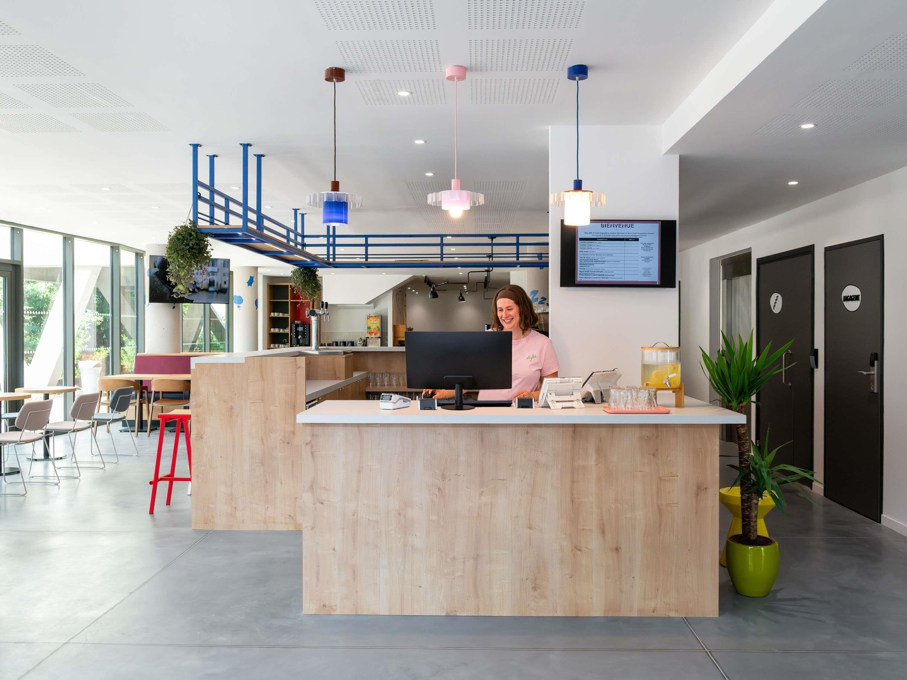 A modern reception area with a wooden counter, a computer, and a digital welcome screen.
