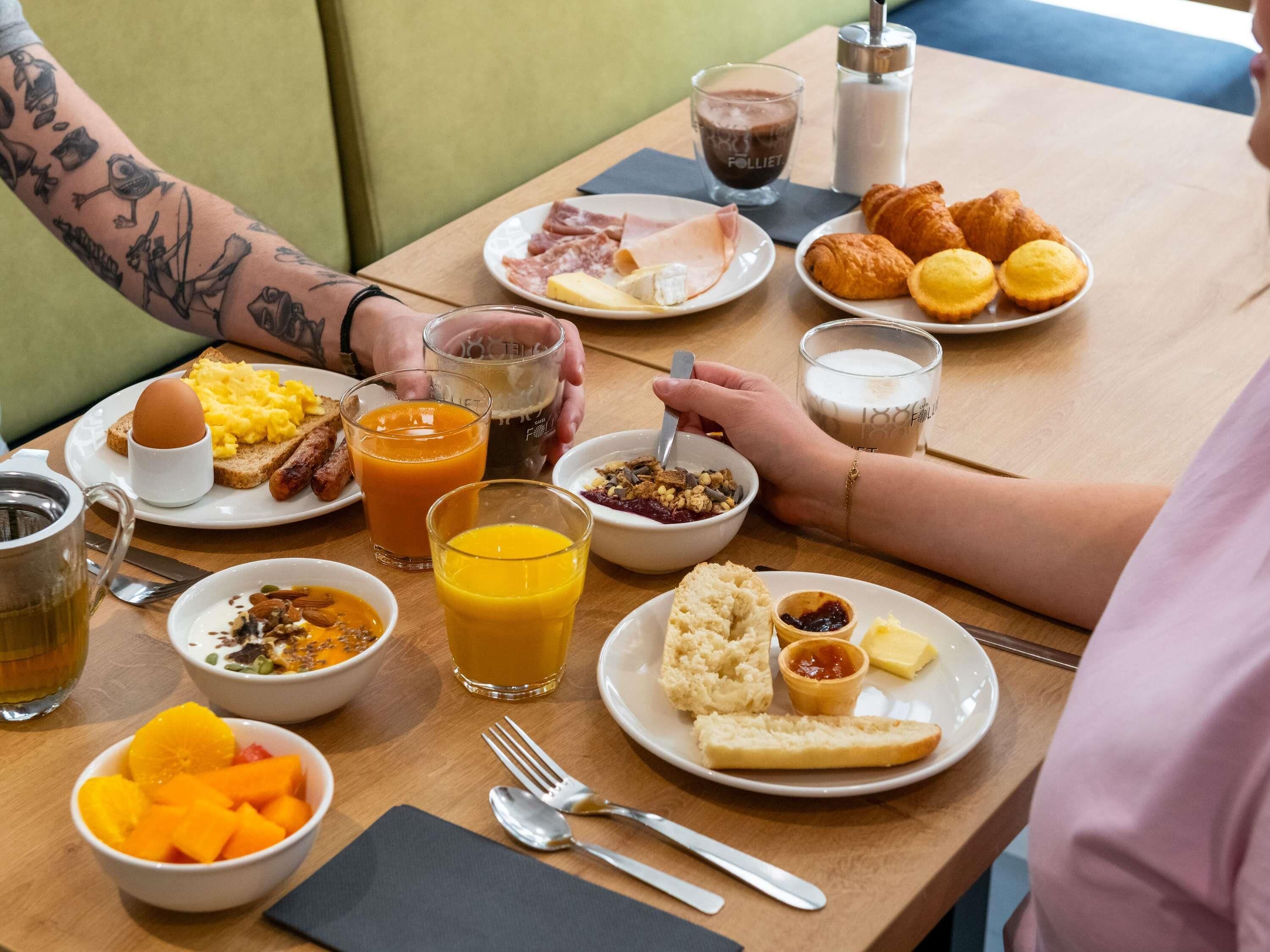 A breakfast setting with various food items and drinks on a wooden table.