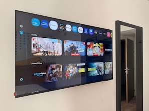 A large flat-screen TV mounted on a wall displaying various streaming services and content.