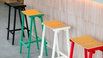 Tres taburetes con asientos de madera y patas de metal en varios colores.