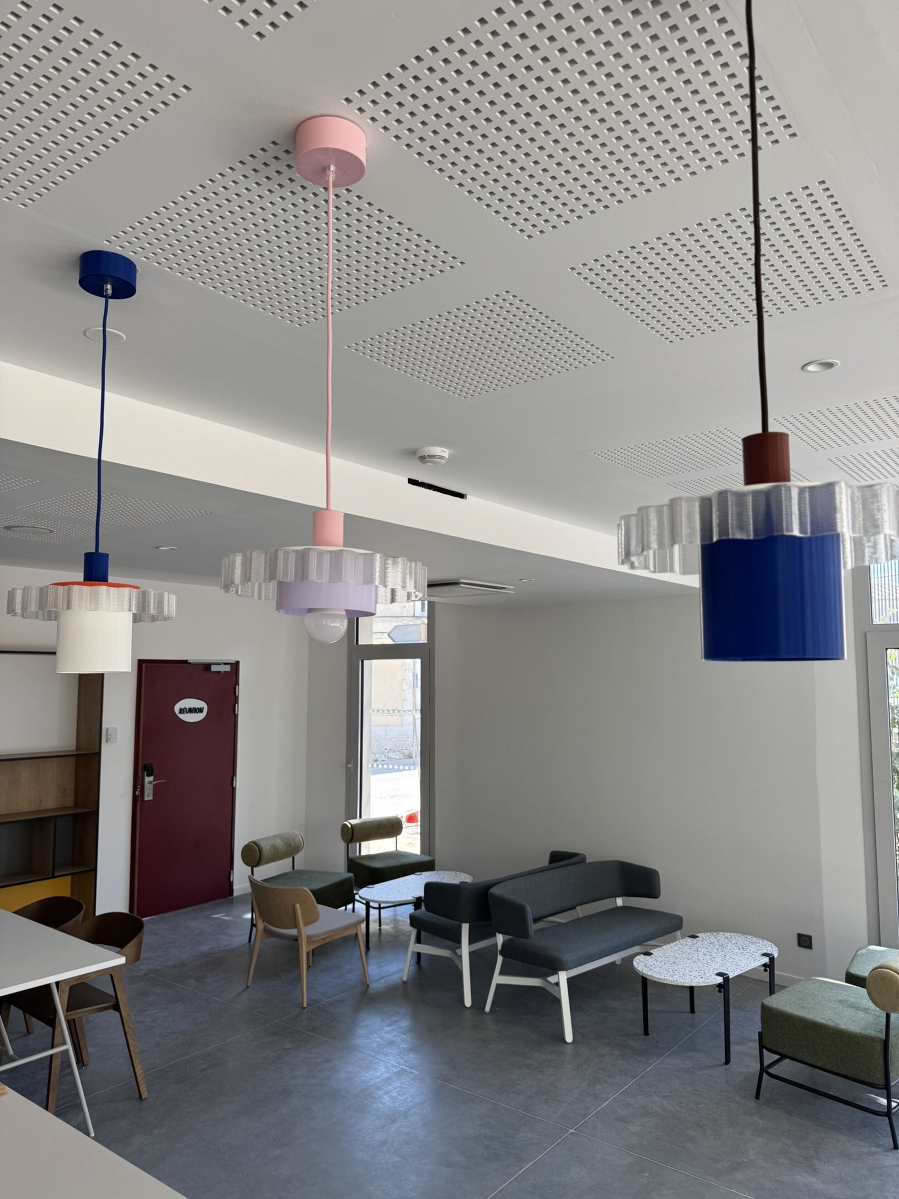 Un intérieur moderne comprenant un espace salon, une porte portant l’inscription « RÉCEPTION » et une fenêtre laissant entrer la lumière naturelle.