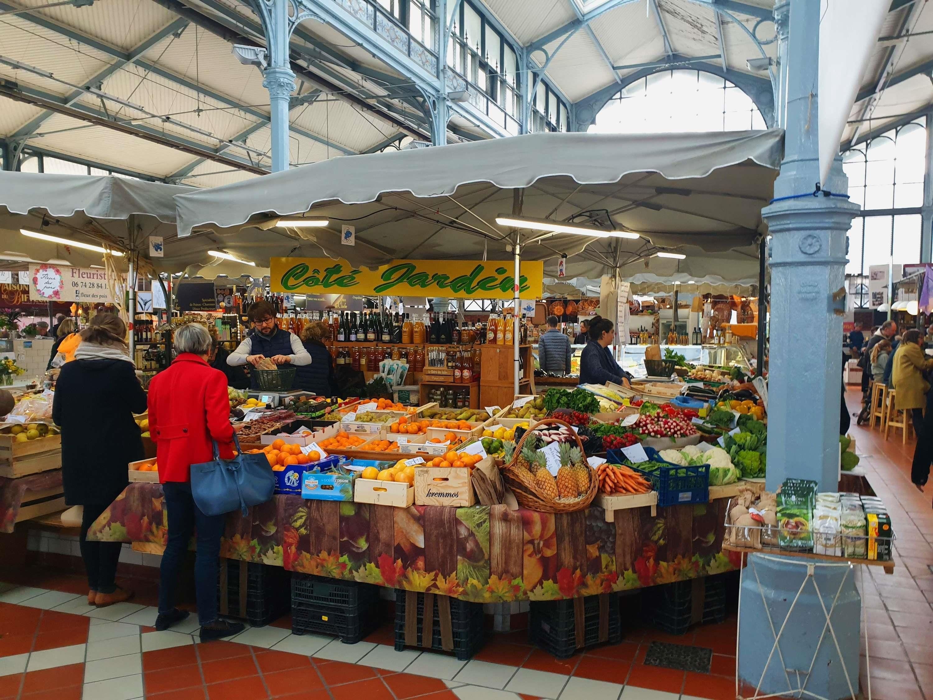 An indoor market with various stalls selling fruits and vegetables.