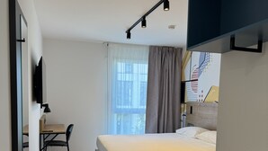 Um quarto moderno com uma cama, uma escrivaninha e uma televisão.