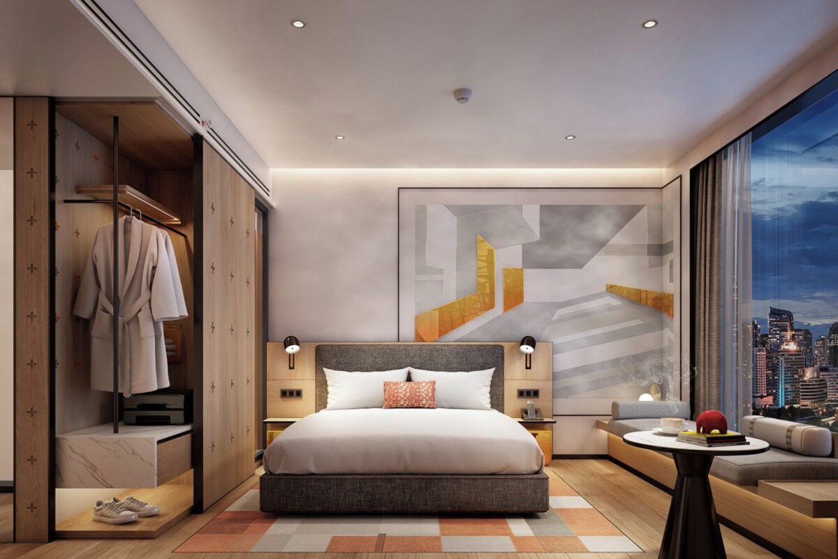 A modern hotel room with a large bed, a seating area, and a city view.