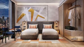 A modern bedroom with a city view, two beds, a seating area, and a walk-in closet.