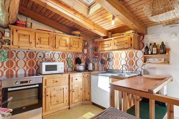 Une cuisine avec des meubles de rangement en bois, un four à micro-ondes, une cuisinière et un évier.