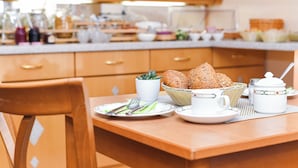 A breakfast table set with plates, cutlery, bread, a cup, and a jug. - Double room incl. breakfast on the North Sea coast (Esens)