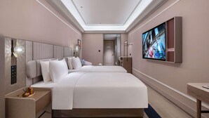 A modern hotel room with a large bed, a flat-screen TV, and a bedside table.